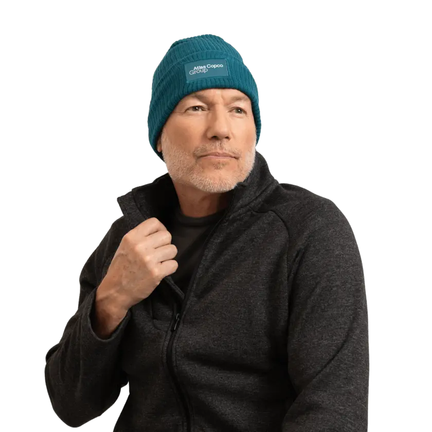 man wearing teal winter hat with atlas copco group logo